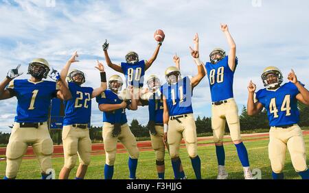 Teenager und junge männliche American Football-Team feiert am Fußballplatz Stockfoto