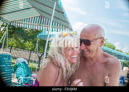 Porträt von liebevollen älteres paar sitzen am Pool am Außenpool Stockfoto