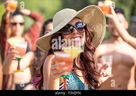 Junge Frau trägt Sonnenhut trinken Cocktails und tanzen im Garten Stockfoto