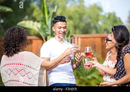 Junger Mann teilen einen rose Wein Toast mit Erwachsenen Schwestern im Garten Stockfoto