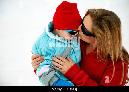 Ski Mutter kleinen Sohn auf Stirn küssen Stockfoto