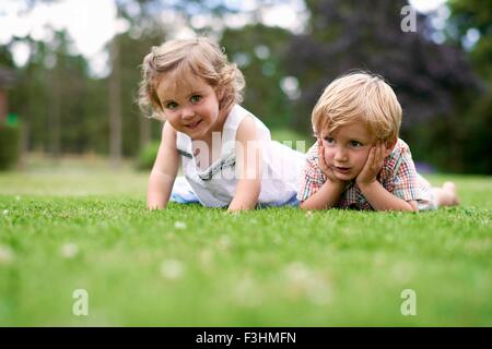 Oberflächenniveau von jungen und Mädchen auf dem Rasen liegend Stockfoto