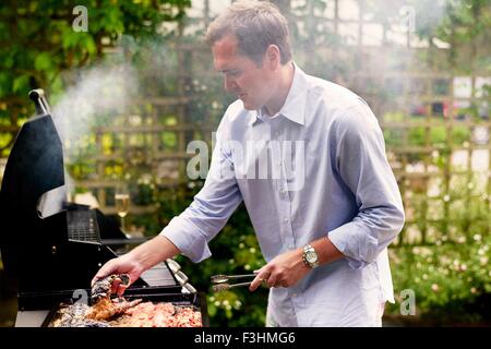 Reifer Mann Kochen Fisch und Meeresfrüchte am Grill Stockfoto