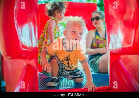 Mutter und Kinder spielen am roten Rutschbahn Stockfoto