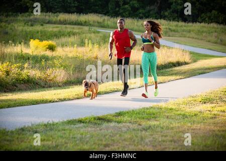 Junges Paar und Hund im Park laufen Stockfoto