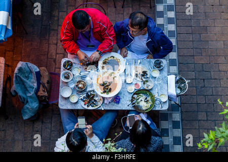 Touristen, die Fisch und Meeresfrüchte essen, während mit Smartphones, königliche Gericht, Carnaby Street, London, UK Stockfoto