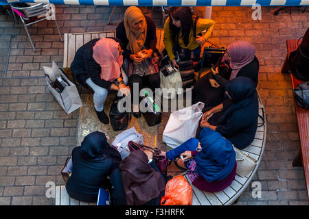 Junge muslimische Frauen sitzen im Chat auf ein Cafe In der Carnaby Street, London, UK Stockfoto