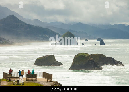 Touristen genießen den Blick auf Haystack Rock und Cannon Beach von einem Aussichtspunkt in Ecola State Park, Oregon. Stockfoto