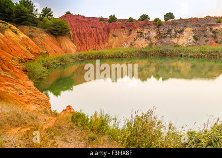 rote Böden rund um den See gebildet, in einem ehemaligen Steinbruch zur Gewinnung von Bauxit in Italien Stockfoto