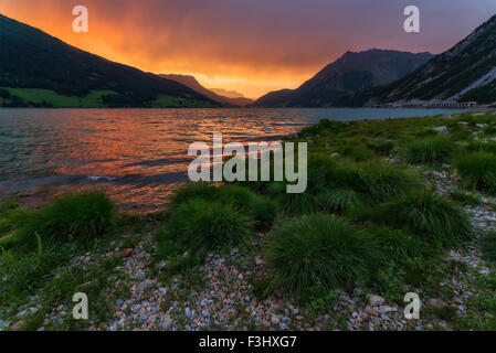 Schöne Aussicht auf den See Resia. Dramatischer Himmel und farbenprächtigen Sonnenuntergang. Alpen, Italien, Europa. Stockfoto