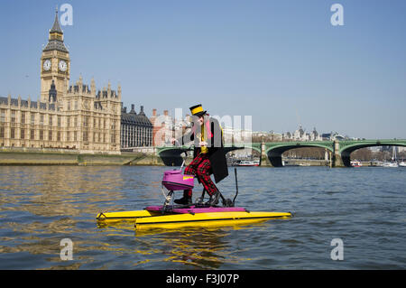 Hackney Monster Raving Loony Party Kandidaten, Nigel Knapp, auf schwimmenden Fahrrad auf der Themse vor dem House of Parliament Stockfoto