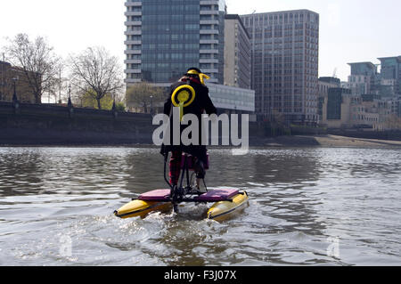 Hackney Monster Raving Loony Party Kandidaten, Nigel Knapp, auf schwimmenden Fahrrad auf der Themse vor dem House of Parliament Stockfoto