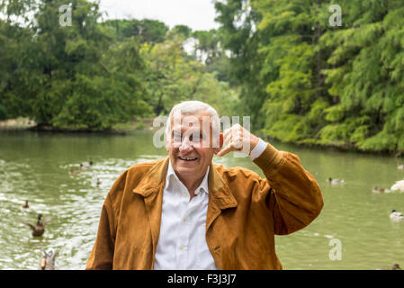 Senior mit Wildleder Jacke und weißes Hemd macht die Geste des Telefons mit hand Stockfoto