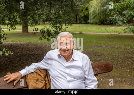 Senior mit Wildleder Jacke und weißes Hemd in einem grünen Park lächelnd Stockfoto