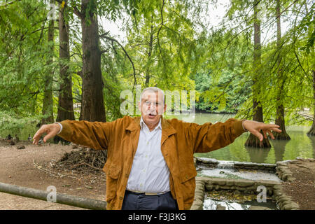 Senior mit Wildleder Jacke und weißes Hemd in einem grünen Park mit offenen Armen Stockfoto