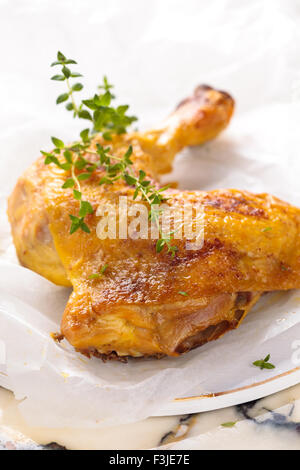 Closeup Aufnahme gebackene Hähnchenschenkel mit Thymian auf Weißes Backpapier. Stockfoto