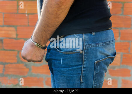 Verhaftung, close-up erschossen Mann die Hände mit Handschellen vor Terrakotta Blöcke Ziegelmauer, linke Seite Stockfoto