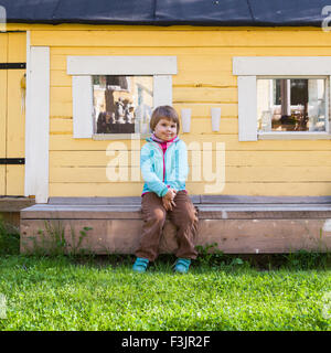 Outdoor Portrait von niedlichen kaukasischen blonde Mädchen in der Nähe von kleinen ländlichen Holzhaus Wand Stockfoto