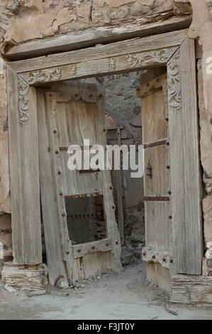 Reich verzierte Holztür in zerstörten Adobe Gebäude in einer Stadt in das Sultanat Oman, eine sichere, freundliche Golfstaat Urlaubsziel Stockfoto