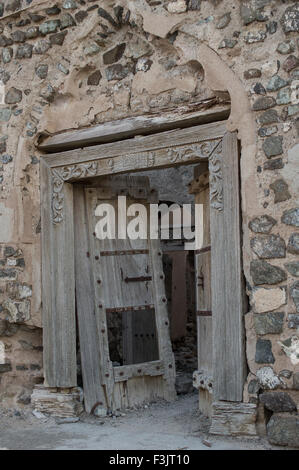 Reich verzierte Holztür in zerstörten Adobe Gebäude in einer Stadt in das Sultanat Oman, eine sichere, freundliche Golfstaat Urlaubsziel Stockfoto