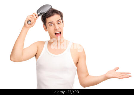Angry Young Man seine Haare mit einer Haarbürste Bürsten und schaut in die Kamera, die isoliert auf weißem Hintergrund Stockfoto