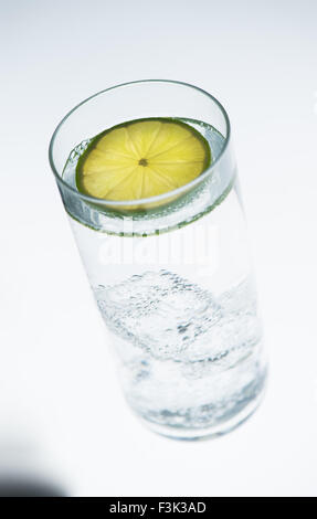 Glas Wasser, Soda oder alkoholische Getränk mit Limettenscheibe auf weißem Hintergrund Stockfoto