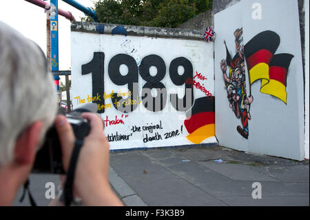 Berlin, Deutschland. 12. Sep, 2015. Ein Mann nimmt ein Bild von einem Berliner Mauer-Segment, das "1989" an der East Side Gallery in Berlin, Deutschland, 12. September 2015 liest. Segmente der Berliner Mauer, ein Wachturm und Grenzschutz, die Fahrzeuge wurden auf dem ehemaligen Gelände des Yaam-Club eingerichtet befindet sich hinter dem Wandsegment. Foto: Paul Zinken/Dpa/Alamy Live News Stockfoto