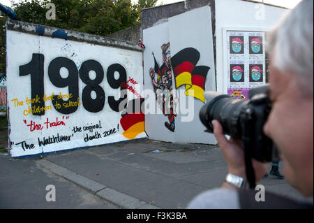 Berlin, Deutschland. 12. Sep, 2015. Ein Mann nimmt ein Bild von einem Berliner Mauer-Segment, das "1989" an der East Side Gallery in Berlin, Deutschland, 12. September 2015 liest. Segmente der Berliner Mauer, ein Wachturm und Grenzschutz, die Fahrzeuge wurden auf dem ehemaligen Gelände des Yaam-Club eingerichtet befindet sich hinter dem Wandsegment. Foto: Paul Zinken/Dpa/Alamy Live News Stockfoto