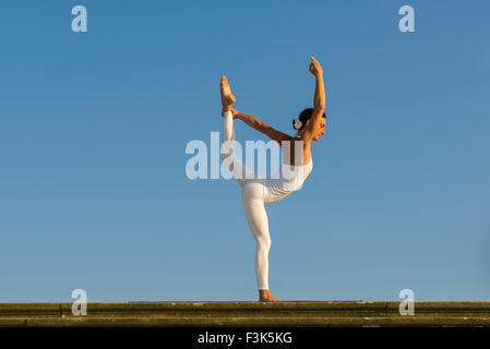 Junge Frau, eine weiße Babybody, übt Hatha-yoga Outdoor, zeigt die Pose: saral natarajasana, vorbereitende Herr Stockfoto