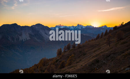 Letzten roten und orangefarbenen Sonnenlicht hinter den majestätischen Gipfeln der Massif des Ecrins (4101 m), Französische Alpen, betrachtet aus der Ferne in Buenos Aires Stockfoto