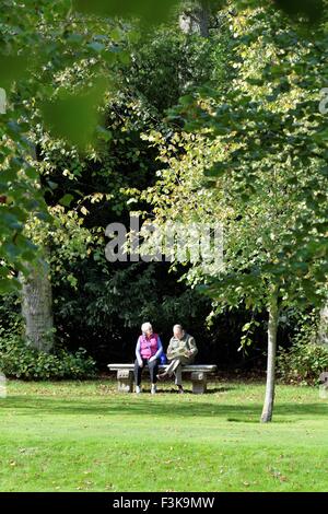 Älteres Paar sitzt auf einer Steinbank in einer Parklandschaft Stockfoto