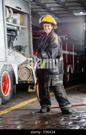 Glücklich Firewoman Besprühen mit Wasser während des Trainings Stockfoto