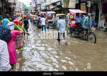 Viele Menschen und Motor Rikschas sind durch die überschwemmten Straßen der Vorstadt paharganj nach einem heftigen Monsun-regen Stockfoto