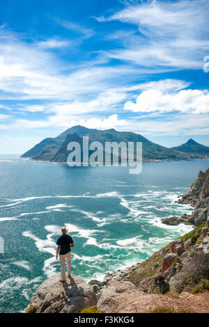 Ein einsamer Wanderer auf Felsen über dem Atlantischen Ozean blickt in Richtung Sentinel Peak, Seelandschaft von Chapmans Peak Laufwerk, A betrachtet Stockfoto