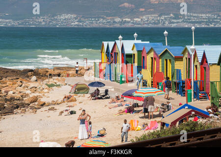 Einheimische am Strand mit Sonnenschirmen und bunte Badehäuschen, St. James Beach Golf Ozean, Südafrika Stockfoto