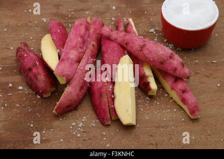 Japanische Süßkartoffeln schneiden Lengthwish auf ein Schneidbrett aus Holz dann mit Seasalt bestreut; fertig gebraten werden. Stockfoto