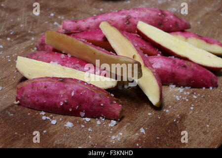 Japanische Süßkartoffeln schneiden Lengthwish auf ein Schneidbrett aus Holz dann mit Seasalt bestreut; fertig gebraten werden. Stockfoto