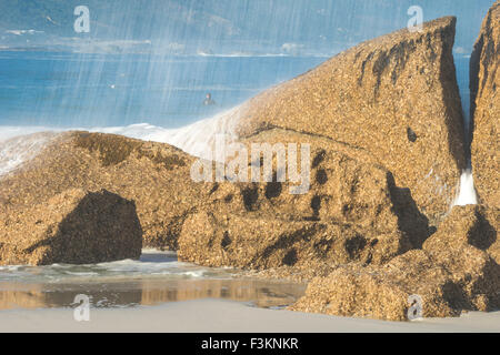 Spray von Ozeanwelle Absturz in Granitblock des Camps Bay Beach bei Dämmerung, Atlantik, Kapstadt, Südafrika Stockfoto