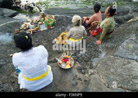 Balinesische Hindu Gläubigen beten bei Sonnenuntergang auf den felsigen Stränden rund um den Tanah Lot Tempel. Stockfoto