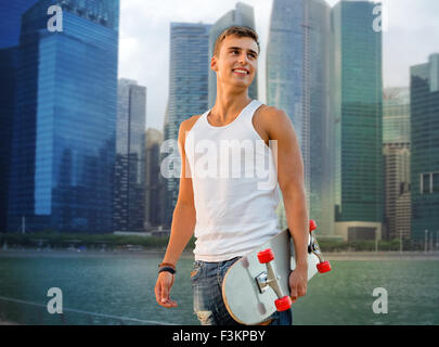 lächelnder Mann mit Skateboard über Singapur Stadt Stockfoto