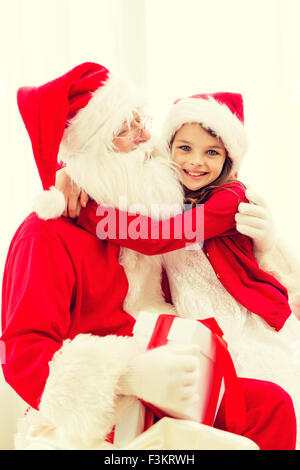 lächelndes Mädchen mit Santa Claus und Geschenk zu Hause Stockfoto