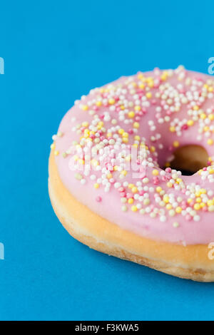Donut mit rosa Zuckerguss und Streusel auf Türkis Stockfoto