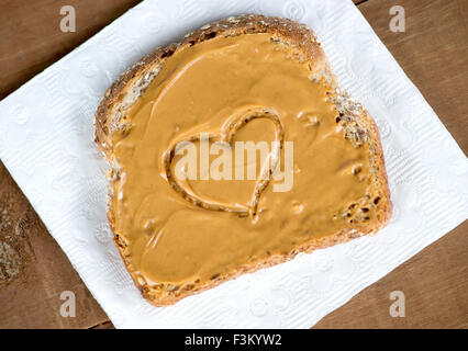 Tosted Peanut Butter Sandwich auf Gewebe gegen Holzbrett mit Herzform Stockfoto