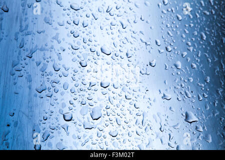 Gebogene Edelstahl-Oberfläche mit Wasser Tropfen, blau getönten Foto mit selektiven Fokus Stockfoto