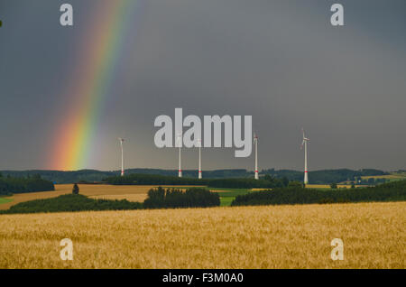 Windkraftanlagen hinter einem ABPFLÜCKEN mit dunklen Wolkenhimmel und Rainbow Stockfoto