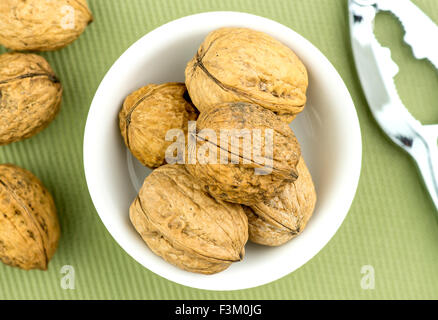 Walnüsse in der Schale mit Nussknacker in der Nähe Stockfoto