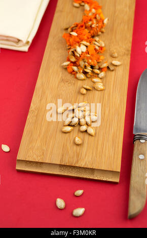Kürbis Squash Samen gegen ein Holzbrett auf roten Tisch Stockfoto