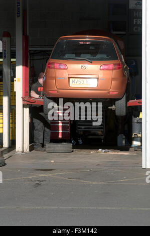 auf Rampe in Garage für Autoreparaturen durch Mechanikerservice Wartung Autos reparieren Reparaturkosten laufen Reifen Reifen Reifen Reifen l Stockfoto