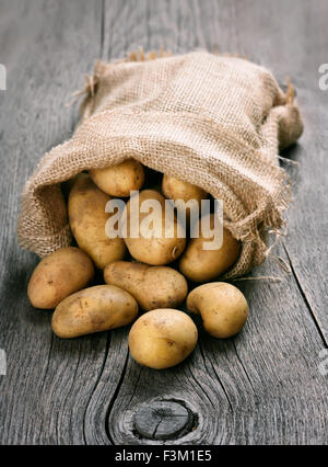 Kartoffeln im Leinensack auf hölzernen Hintergrund konzentrieren sich auf Kartoffel vor Stockfoto