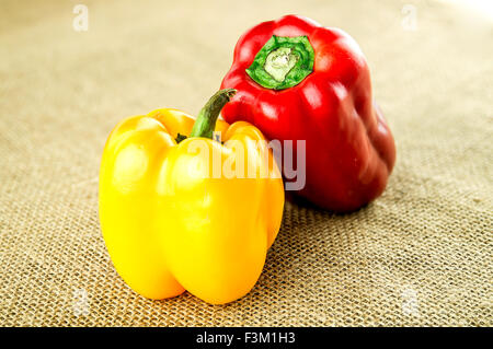 Rote und gelbe Paprika auf rustikalen Sackleinen Stockfoto